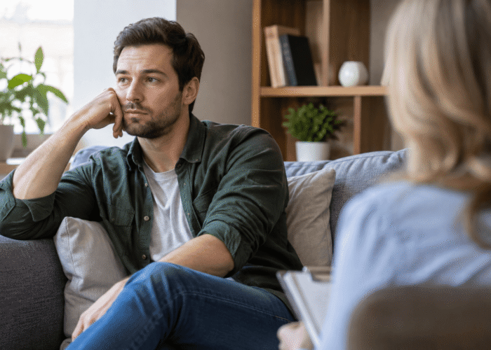 Anhedonia in Addiction Recovery Man experiencing anhedonia during addiction recovery while talking with a counselor in a therapy session.