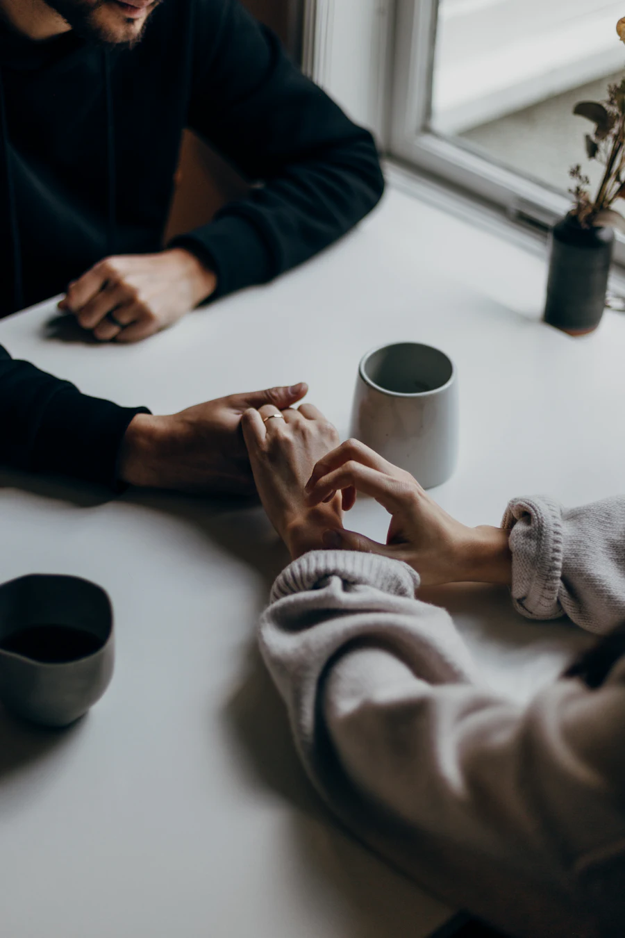 A couple holding hands across a table during a conversation