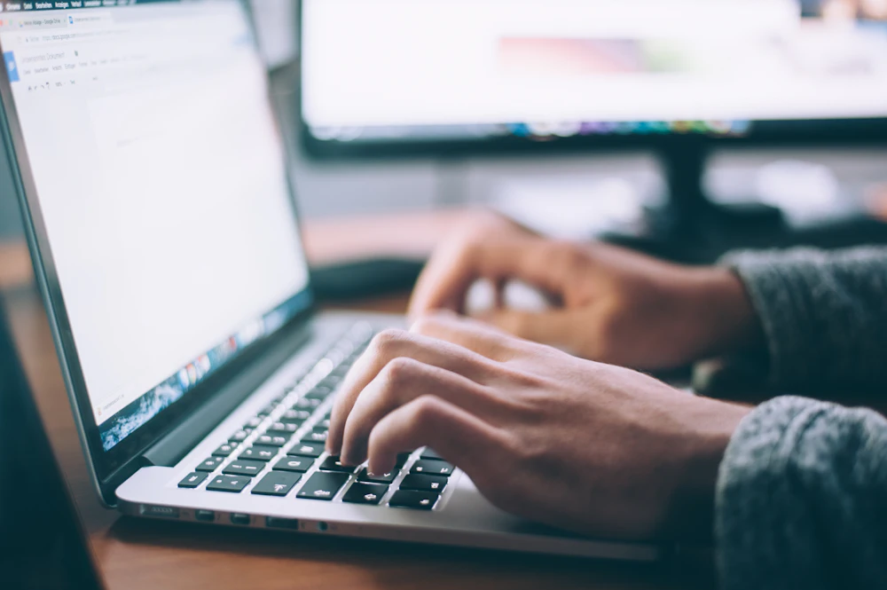 Close-up of a person typing on a laptop, with their face outside the frame
