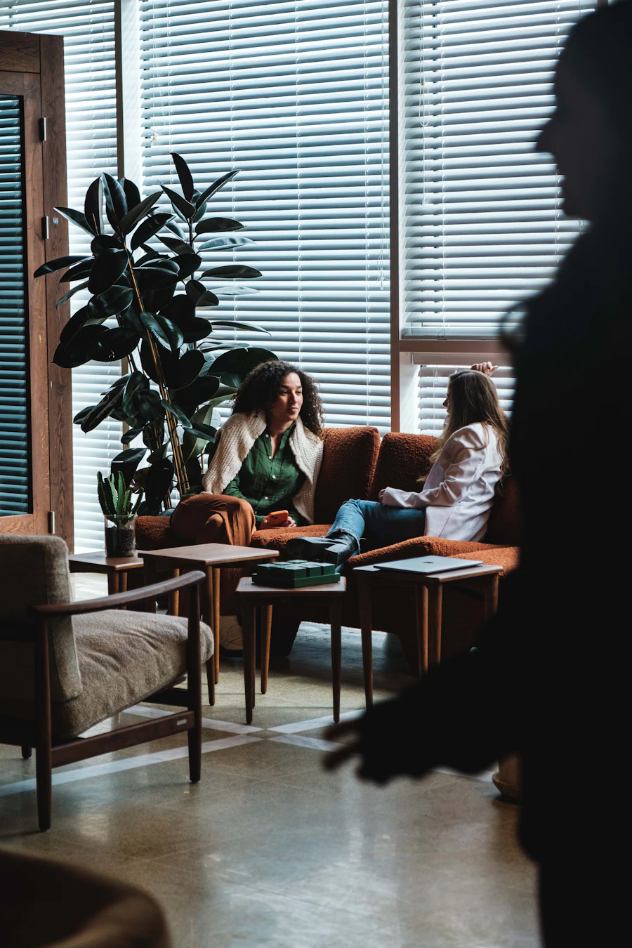 Two women seated together in conversation beside a window