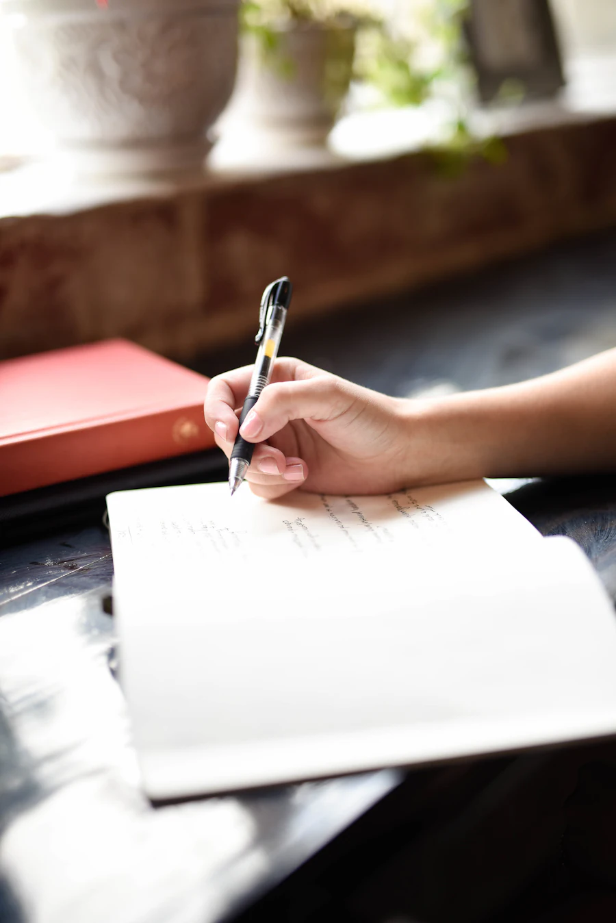 Close-up of a person writing by hand in an open notebook